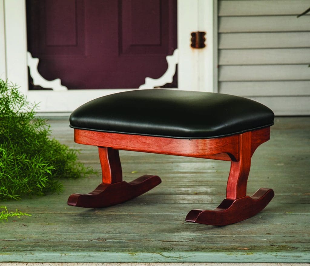 Rocking Tommy Footstool with a stained hardwood base and black leather upholstery.