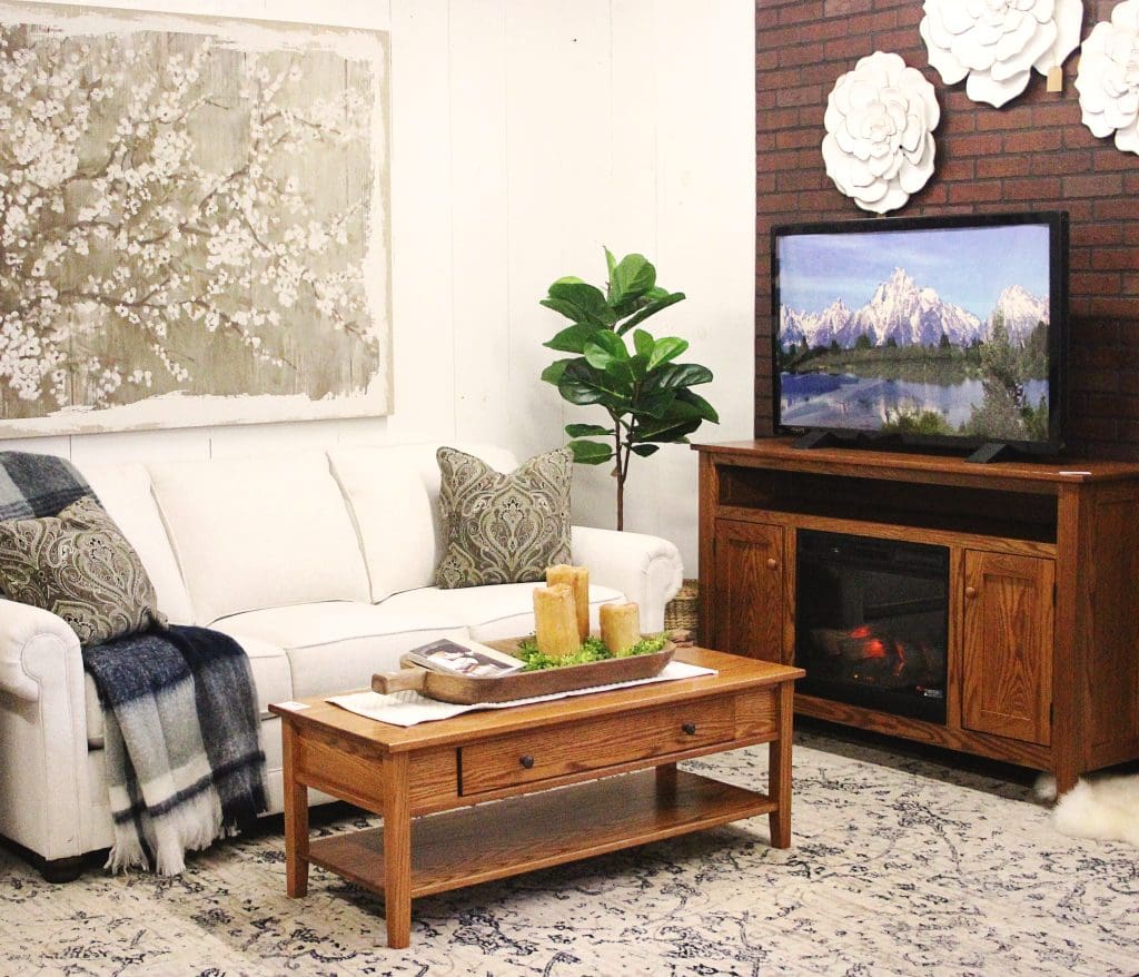 Living room with a hardwood coffee table, an off-white sofa, a beige throw pillow, and an indoor fiddle leaf fig plant.