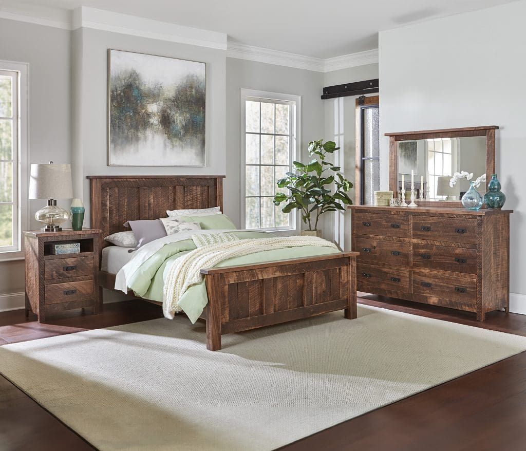 Bedroom with light gray walls, brown wood flooring, a large white rug, a hardwood rough sawn Dumont bed, and a matching rough sawn dresser and nightstand.