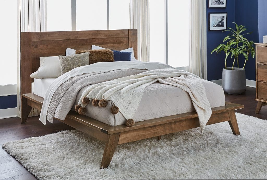 Brown hardwood contemporary style bed with white bedding inside a bedroom with navy blue walls, white curtains, and a large white shag rug.