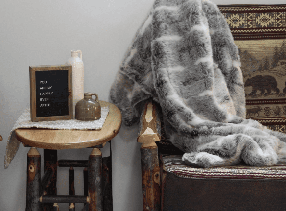 Hickory lodge side table and couch with a blanket, bear fabric, and some art and pottery on the table