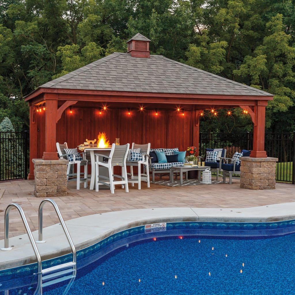 Grey and white round firetable in pub height with matching grey and white poly furniture chairs around it next to a pool.