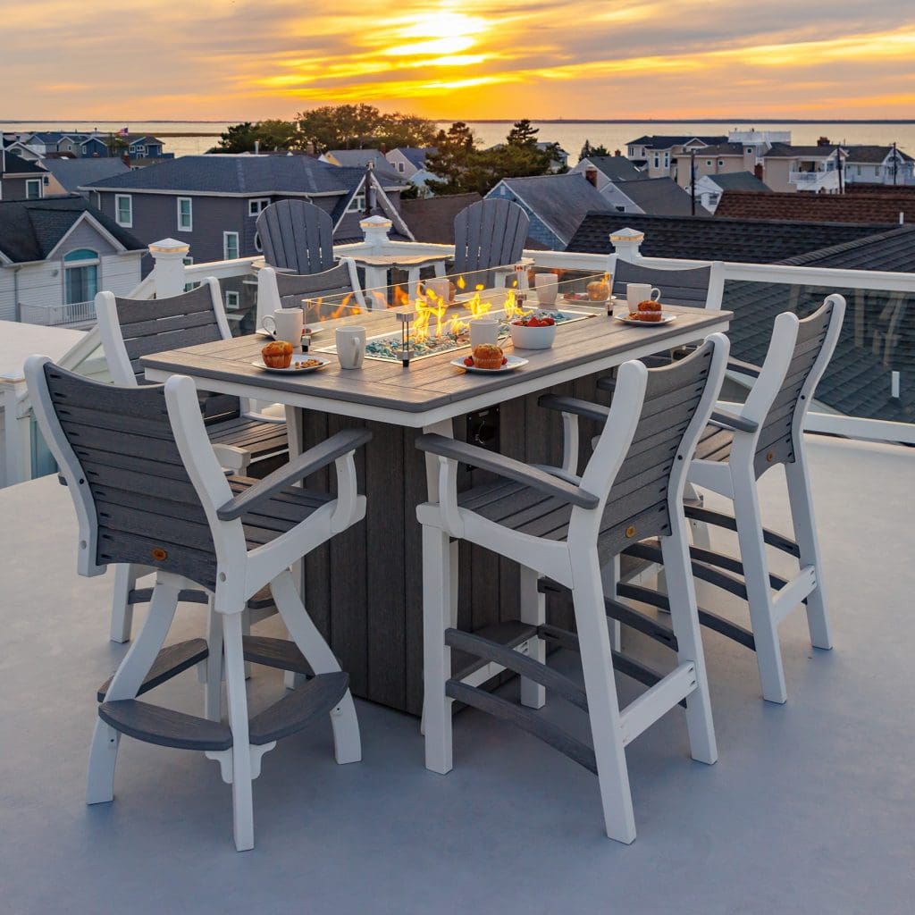 Grey and white rectangle firetable with matching grey and white poly furniture chairs and grey and white swivel chairs around it on a roof top deck.