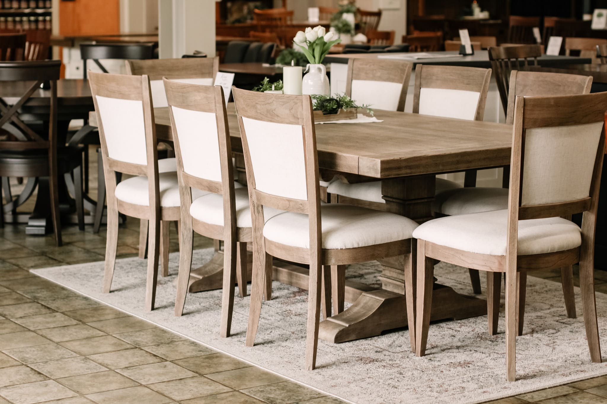 Tuscany dining set with a rectangle light wood trestle table and 8 white and light wood chairs.